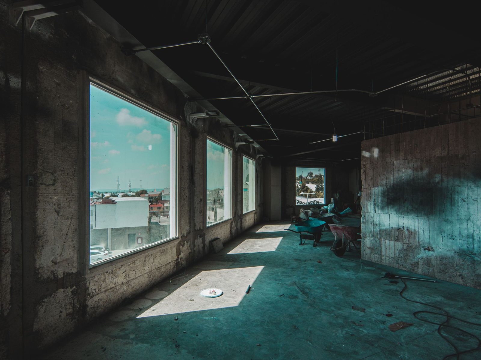 Unfinished concrete floor with large windows and wheelbarrows